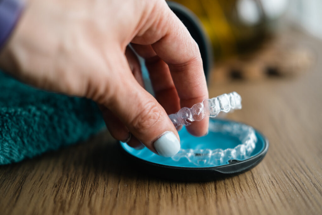 A custom acrylic night guard for bruxism being placed in a protective storage case.
